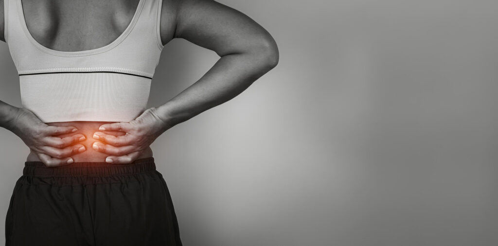 Person holding their lower back in pain from poor posture